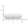 Een witte capsulepil ligt naast een liniaal. De lengte is ongeveer 2 centimeter. miniatuur