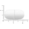 Een Vitakruid - Magnesium 200 Complex® tablet, die wit en ovaal is met een breukstreep, wordt naast een liniaal gelegd om de hoeveelheid te meten. miniatuur