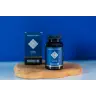 Een flesje MindScopic - CLEAR FOCUS™ Capsules (50 stuks) met een blauw etiket staat op een houten dienblad naast de bijbehorende doos, tegen een blauwe achtergrond. miniatuur
