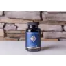 Een flesje MindScopic - CLEAR FOCUS™ Capsules (50 stuks) staat op een licht oppervlak voor een stenen muur. miniatuur