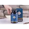 Een fles MindScopic - CLEAR FOCUS™ Capsules (50 stuks) wordt getoond voor de doos, met op de achtergrond een hand die naar een kom reikt en koffiebonen verspreid op het oppervlak. miniatuur