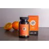 Een flesje en doosje MindScopic - MOODMASTER™ capsules (50 stuks) staan afgebeeld op een grijs vlak met twee sinaasappels op de achtergrond. miniatuur