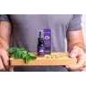 Een persoon houdt een houten plank vast met verse munt, kamillebloemen en een MindScopic - SLEEPWELL SPRAY met melatonine (15ml) flesje en doosje. miniatuur