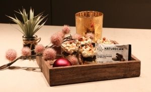 een houten dienblad met een kaars en wat bloemen.