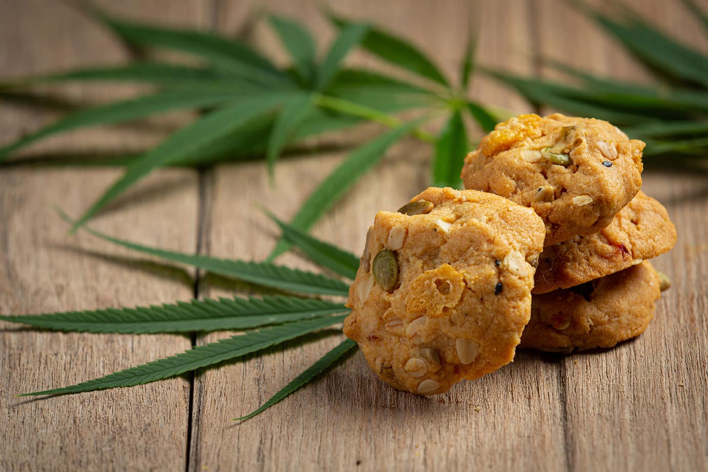 Cbd-koekjes met cannabisbladeren op een houten tafel.